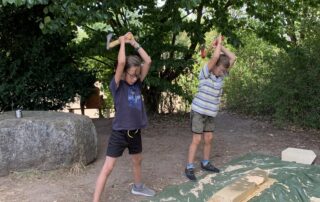 Zwei Kinder versuchen sich am Hacken von Holz