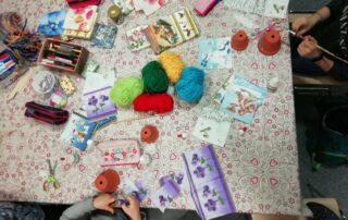 Ein Tisch mit viel Bastelmaterial, wie zum Beispiel Tontöpfen, Wolle, Pinseln und Servietten