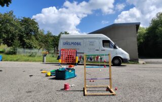 Das Spielmobil auf einem Platz mit verschiedenen aufgebauten Spielgeräten