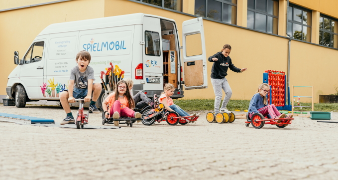 Spielende Kinder vor dem Spielmobil