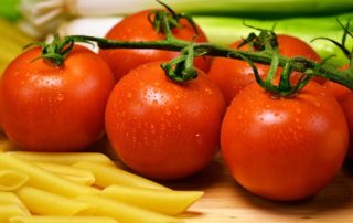 Tomaten auf einem Brett zwischen Nudeln