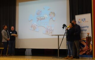 Die DLRG Jugend stellt auf der Bühne ihr Puzzleteil im Rahmen der 75 Jahrfeier des Kreisjugendrings Haßberge vor. Auf der Leinwand ist das Puzzleteil zu erkennen.