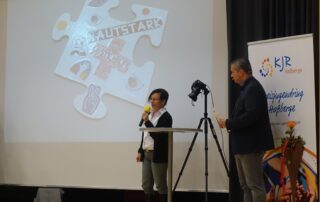 Das Jugendrotkreuz stellt auf der Bühne ihr Puzzleteil im Rahmen der 75 Jahrfeier des Kreisjugendrings Haßberge vor. Auf der Leinwand ist das Puzzleteil zu erkennen.