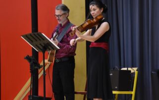 Die Musiker Regine Brand (Geige) und Klaus Neubert (Gitarre) stehen auf der Bühne vor einem Notenständer