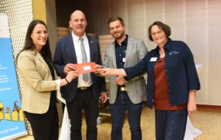 Geschäftsführerin Eva Pfeil übernimmt gemeinsam mit Susanne Makowski und Thomas Wagenhäuser eine Spende der Stadt Haßfurt zum 75. Jubiläum des Kreisjugendrings. Alle greifen gemeinsam zum Spendenumschalg