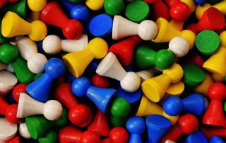 Viele Spielsteine in den Farben gelb, grün, blau, rot und weiß liegen durcheinander