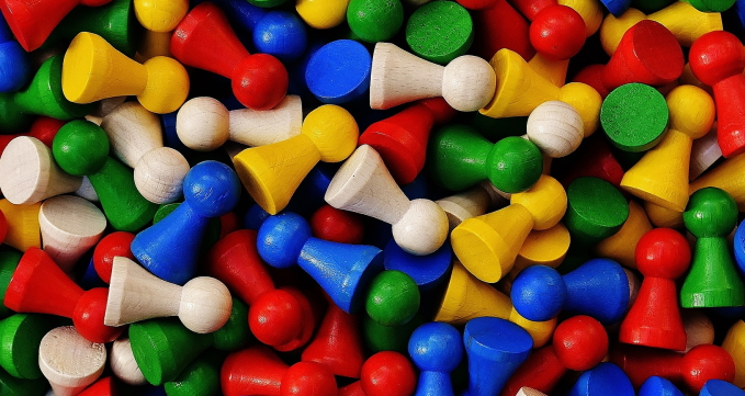 Viele Spielsteine in den Farben gelb, grün, blau, rot und weiß liegen durcheinander