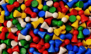 Viele Spielsteine in den Farben gelb, grün, blau, rot und weiß liegen durcheinander