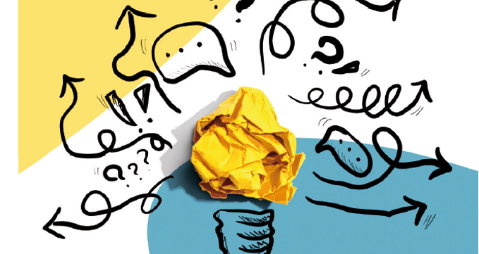 Eine Glühbirne aus geknülltem Papier vor zwischen vielen Zeichen, die Brainstorming darstellen
