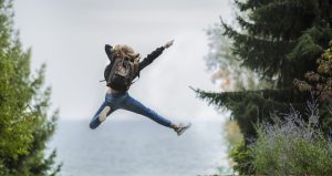 Eine Person springt mit ausgestreckten Gliedmaßen in die Luft zwischen Bäumen.