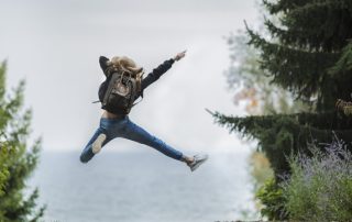 Eine Person springt mit ausgestreckten Gliedmaßen in die Luft zwischen Bäumen.