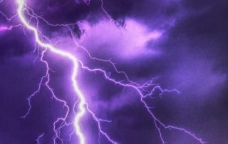 Ein Blitz färbt den bewölkten Himmel lila