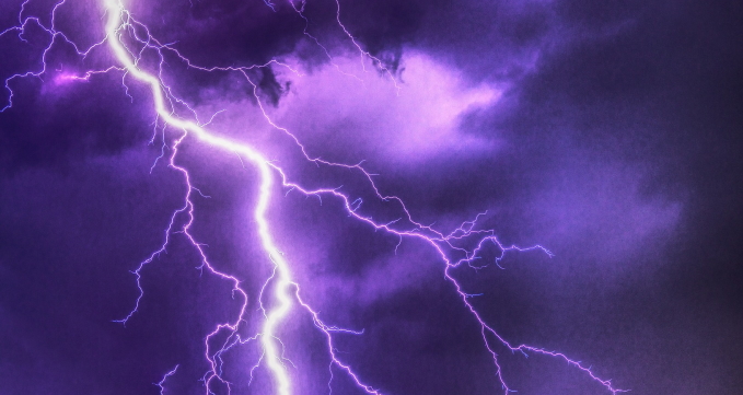 Ein Blitz färbt den bewölkten Himmel lila