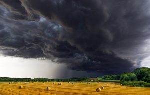 Ein Feld mit Strohballen unter einem sehr dunklen Himmel kurz vor einem Gewitter