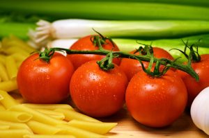 Tomaten auf einem Brett zwischen Nudeln