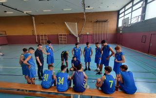 Eine Mannschaft jugendlicher Basketballspieler stehen im Kreis
