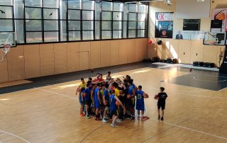 Jugendliche bei einem Basketballtraining in einer Traube im Mittelkreis