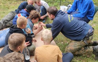 Die Kinder beim inklusiven Zeltlager pusten in Flaschen und erkunden das Element Luft