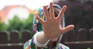 Person hebt Hand nach vorne und vors Gesicht als "Halt" Zeichen