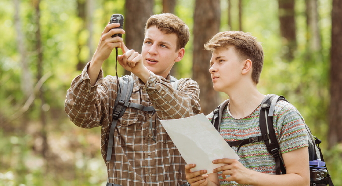 Zwei Personen stehen im Wald und betrachten gemeinsam eine Karte und ein GPS Gerät