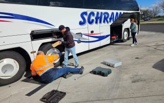 Zwei Personen versuchen Reparatur am Reifen eines großen Reisebusses