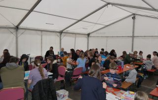 Foto aus dem Zelt mit spielenden Menschen an Tischen