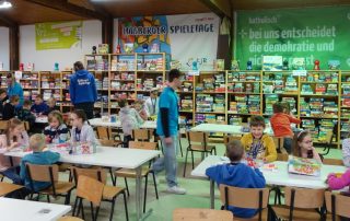 Blick durch die Halle auf das Regal mit den Spielen