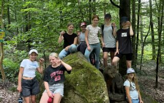 Jugendliche posieren in einer Gruppe an einem Felsen in einem Wald