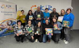 13 Spielerklärerinnen und Spielerklärer mit verschiedenen Spielen in der Hand, beim Vortreffen der Spielerklärer 2025.