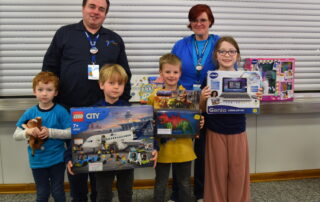 Spieletage-Leitung Wolfgang Winter, Turnier-Leitung Tamara Gräb und die Gewinner des Kinderspiel des Jahres Turnier mit ihren Gewinnen Lego-Flugzeug, Lern-Laptop und Spielzeug-Dinosaurier