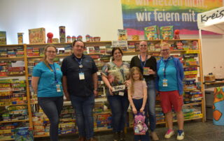 Spieletage-Leitung Wolfgang Winter, Turnier-Leitungen Julia Dinkel und Elisabeth Dürr mit den Gewinnern des Kniffel-Turniers mit ihren Gewinnen "Tabu"-Spiel, "Lama"-Spiel und rosa Teddybär