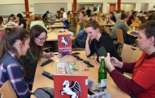 Spielerklärerin vom Pegasus Spielverlag erklärt 3 Personen ein Spiel
