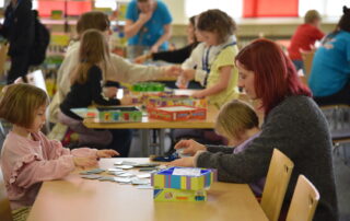 Frau spielt bei den Haßberger Spieletagen mit 2 Kindern Memory