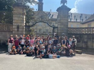 Rund 45 Kinder und 20 Teammitglieder stehen vor dem großen Tor vom Wildpark Schloss Tambach für ein Gruppenfoto zusammen.