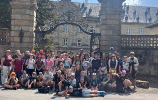 Rund 45 Kinder und 20 Teammitglieder stehen vor dem großen Tor vom Wildpark Schloss Tambach für ein Gruppenfoto zusammen.