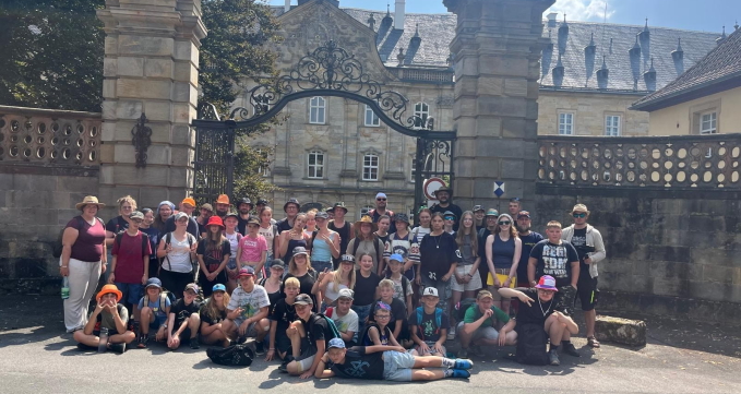 Rund 45 Kinder und 20 Teammitglieder stehen vor dem großen Tor vom Wildpark Schloss Tambach für ein Gruppenfoto zusammen.