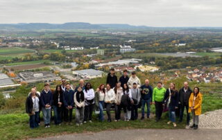 Ein Teil der israelischen Gruppe steht mit Gastfamilien am Aussichtspunkt vom Zeiler Käppele, im Hintergrund sieht man die Aussicht auf die Stadt Zeil und den Steigerwald.